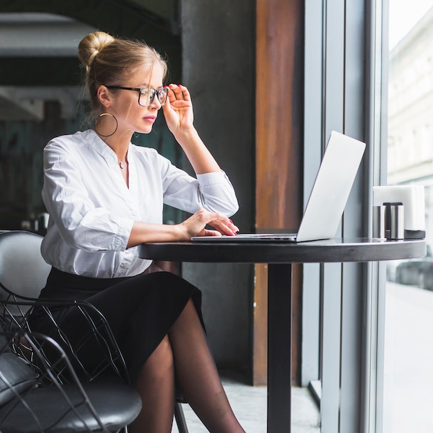 Junge Frau, die an Laptop im Restaurant arbeitet