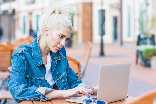 Junge Frau, die an Laptop über hölzernem Schreibtisch arbeitet