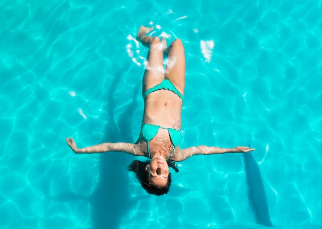 Junge Frau, die an zurück in Pool schwimmt