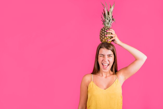 Junge Frau, die Ananas auf Kopf hält