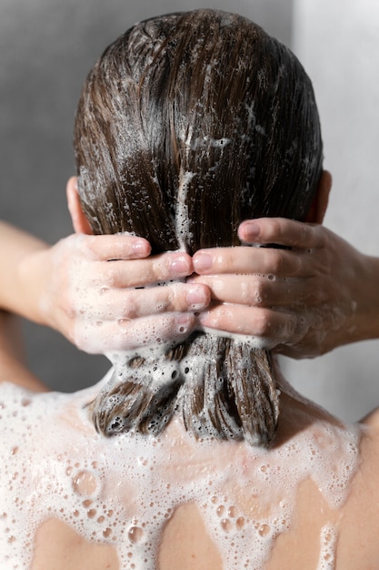 Junge Frau, die Anti-Schuppen-Produkt anwendet