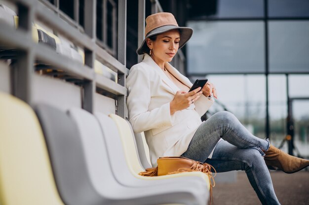 Junge Frau, die auf Arenasitzen sitzt und am Telefon spricht