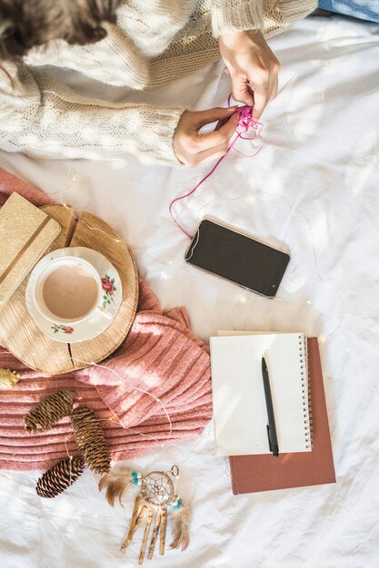 Junge Frau, die auf Bett mit Kaffee und Handy liegt