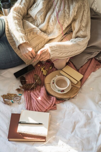 Junge Frau, die auf Bett mit Tasse Kaffee sitzt