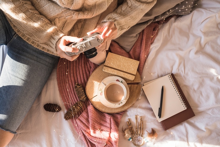 Kostenlose Foto junge frau, die auf decke mit fotokamera sitzt