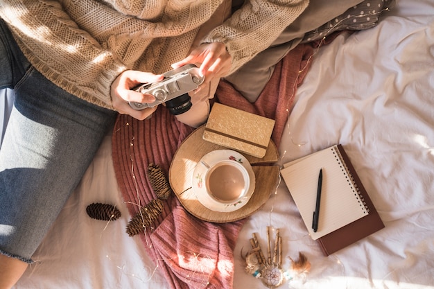 Junge Frau, die auf Decke mit Fotokamera sitzt