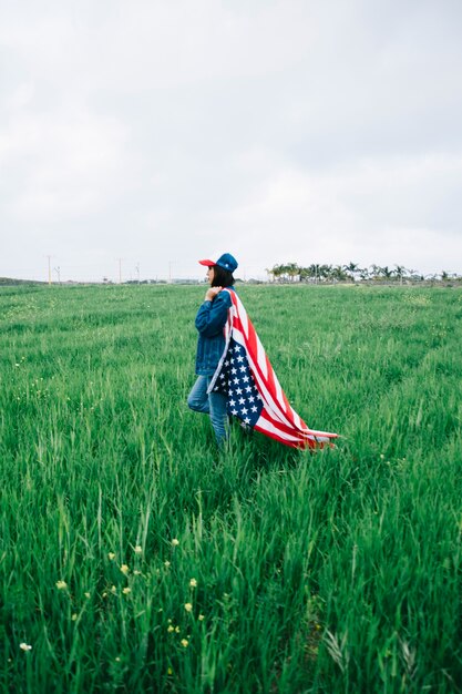 Junge Frau, die auf dem Gebiet mit amerikanischer Flagge bleibt