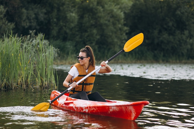 Junge Frau, die auf dem See Kayak fährt