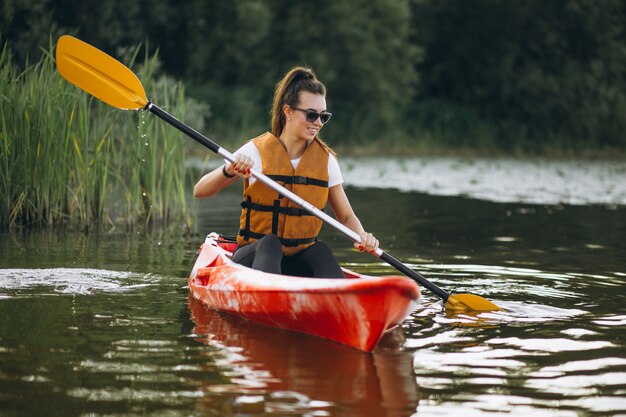 Junge Frau, die auf dem See Kayak fährt