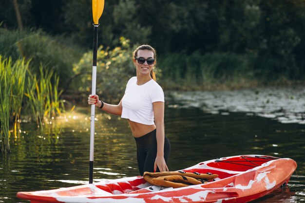 Junge Frau, die auf dem See Kayak fährt