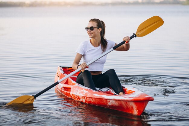 Junge Frau, die auf dem See Kayak fährt