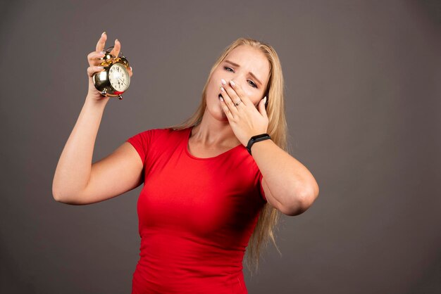 Junge Frau, die auf dunklem Hintergrund gähnt. Hochwertiges Foto