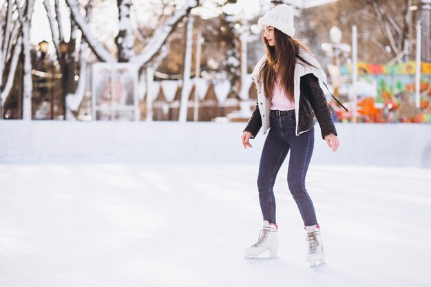 Junge Frau, die auf eine Eisbahn in einem Stadtzentrum eisläuft