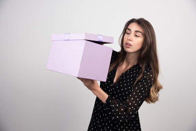 Junge Frau, die auf eine lila Geschenkbox schaut