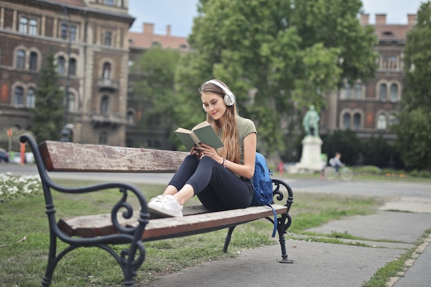 Junge Frau, die auf einer Bank sitzt, liest ein Buch