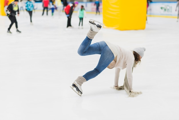 Kostenloses Foto junge frau, die auf eisbahn fällt