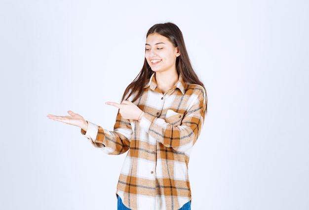 junge Frau, die auf etwas an der weißen Wand zeigt.