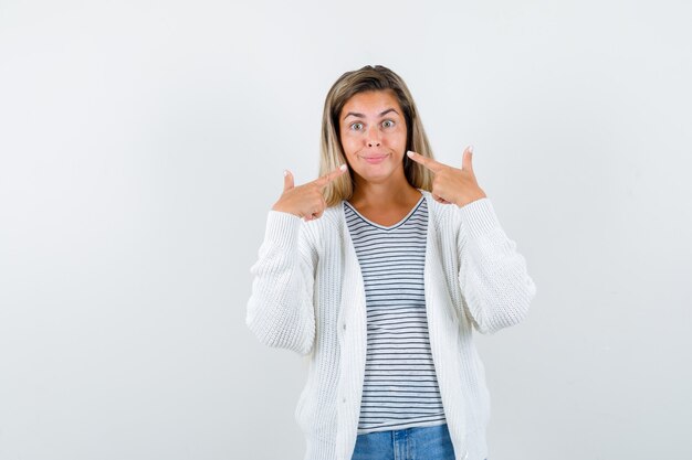 Junge Frau, die auf ihr Lächeln im T-Shirt, in der Jacke und in der niedlichen Vorderansicht zeigt.