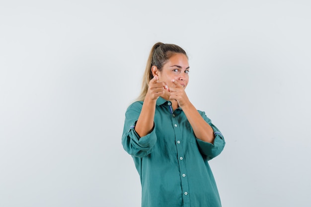 Kostenloses Foto junge frau, die auf kamera im blauen hemd zeigt und konzentriert schaut