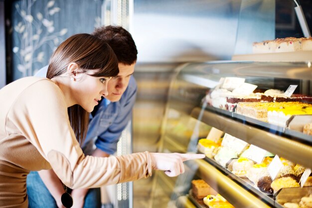 Junge Frau, die auf Kuchen in Süßwaren zeigt