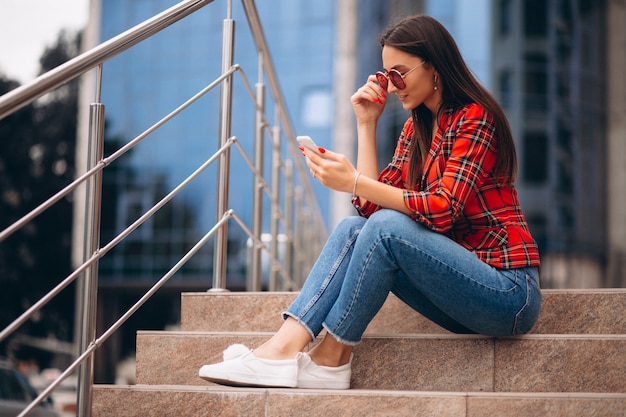 Junge Frau, die auf Treppen sitzt und am Telefon spricht