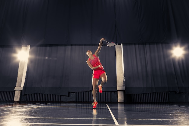 Junge Frau, die Badminton im Fitnessstudio spielt