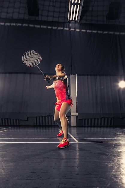 Junge frau, die badminton im fitnessstudio spielt