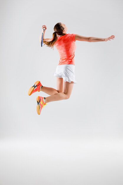 Junge Frau, die Badminton über Weiß spielt