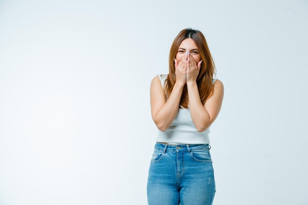 Junge Frau, die beim Lachen Mund und Nase mit den Händen bedeckt