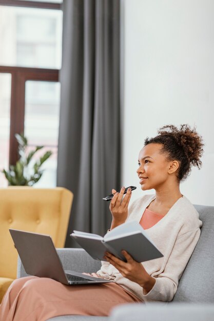 Junge Frau, die beim Sitzen auf dem Sofa arbeitet