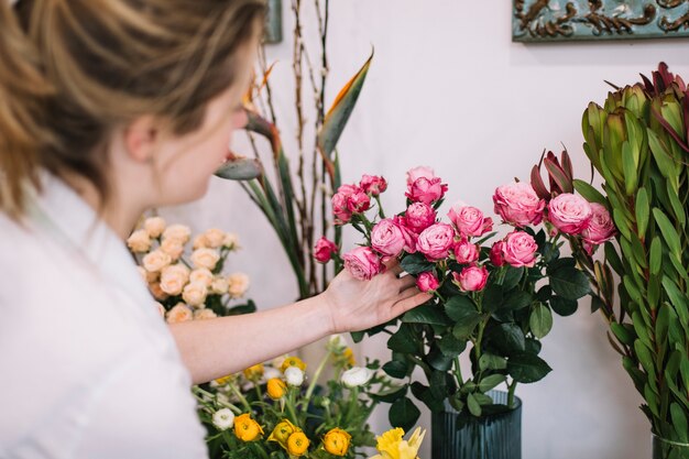 Junge Frau, die Blumen im Shop anordnet