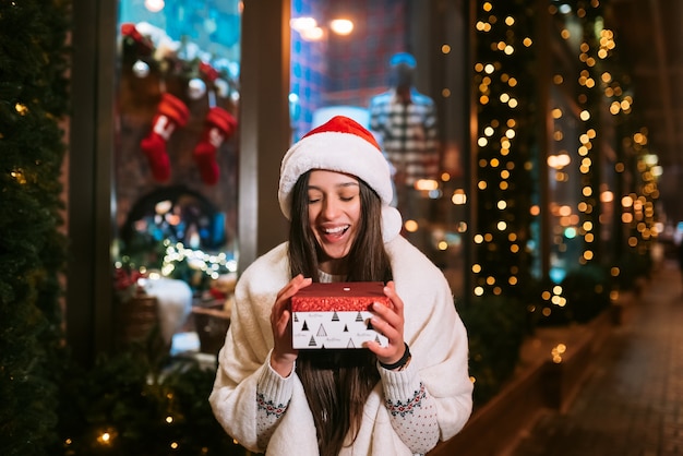 Junge Frau, die Box für Sie im Freien in der Winterstraße gibt Geschenkaustauschkonzept.