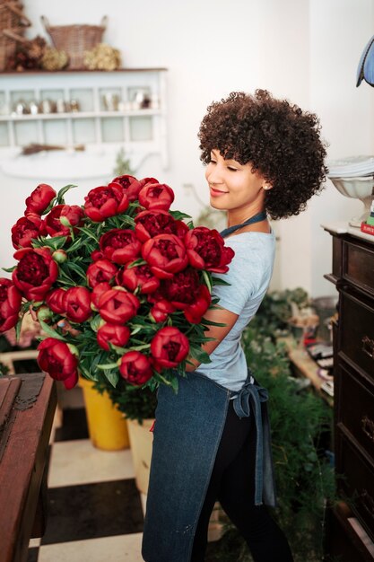 Junge Frau, die Bündel rote Blumen im Shop hält