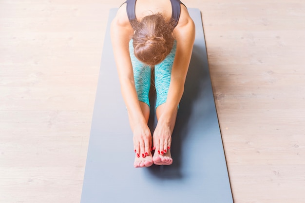 Junge Frau, die Übung auf Yogamatte ausdehnend tut