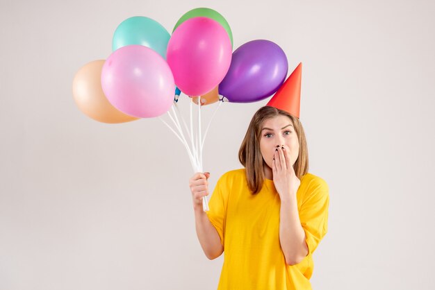 junge Frau, die bunte Luftballons auf Weiß hält