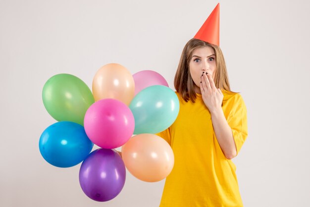 junge Frau, die bunte Luftballons auf Weiß hält