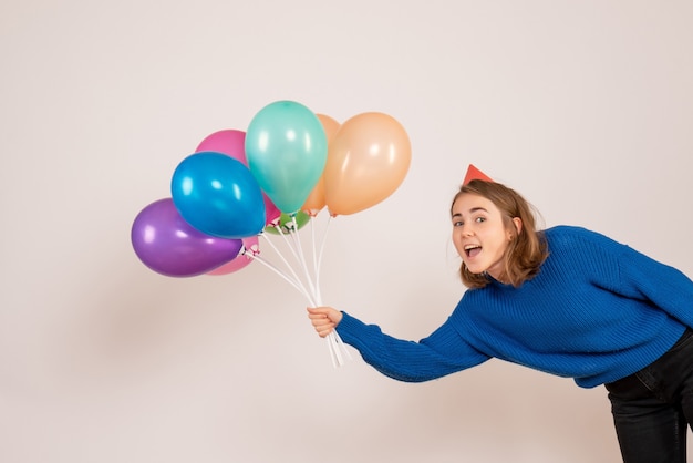 junge Frau, die bunte Luftballons auf Weiß hält