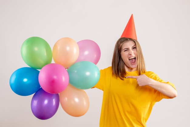 junge Frau, die bunte Luftballons auf Weiß hält