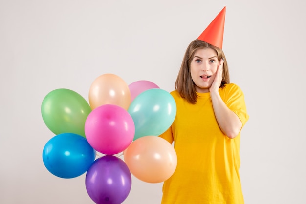 junge Frau, die bunte Luftballons auf Weiß hält