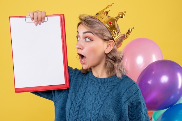 Kostenloses Foto junge frau, die bunte luftballons und anmerkung auf gelb hält