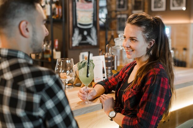 Junge Frau, die das Glas Getränk datiert von ihrem Freund hält