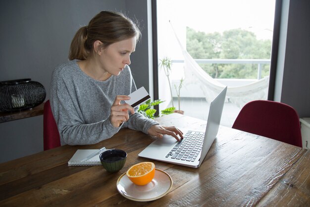 Junge Frau, die das on-line-Einkaufen mit Kreditkarte auf PC macht