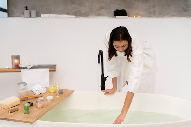 Junge Frau, die das Wasser überprüft, bevor sie ein Bad nimmt