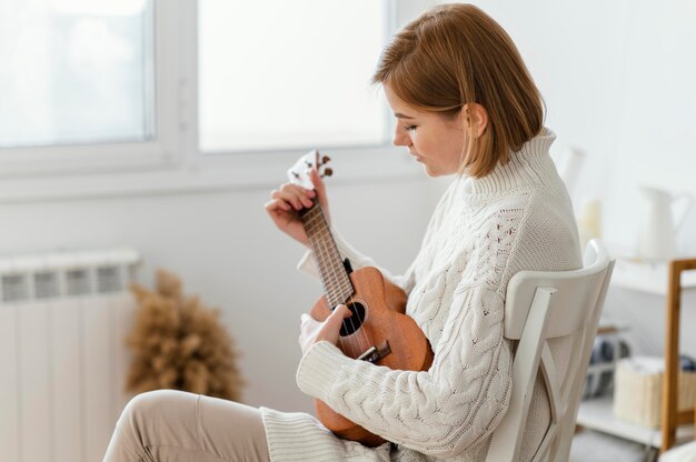 Junge Frau, die die Ukulele spielt