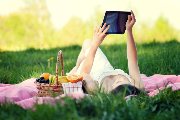 Junge Frau, die digitales Tablett auf Wiese benutzt