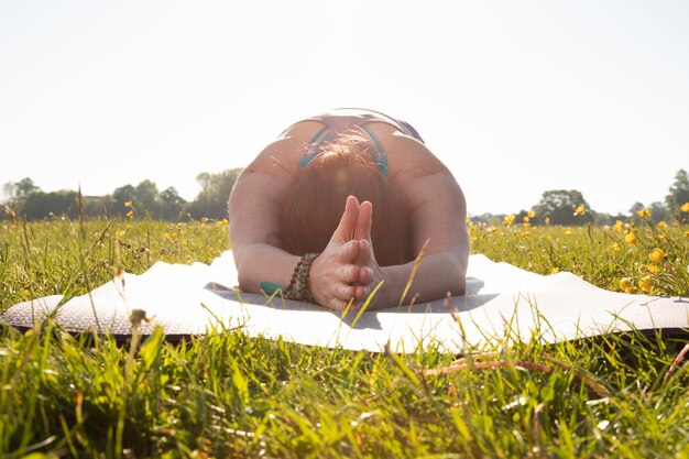 Junge Frau, die draußen auf Yogamatte meditiert