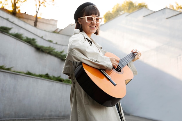 Junge frau, die draußen gitarre spielt