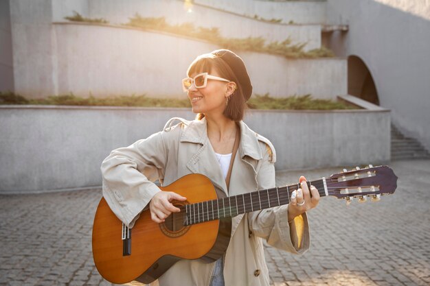 Junge Frau, die draußen Gitarre spielt