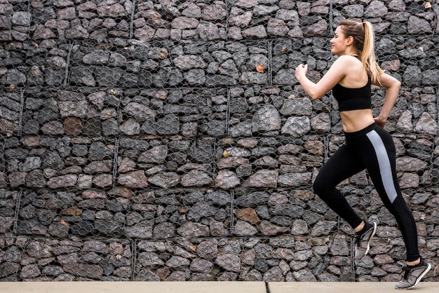 Junge Frau, die draußen mit Sportkleidung läuft