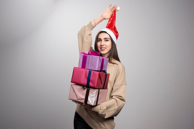 Junge Frau, die drei Kisten der Weihnachtsgeschenke trägt.